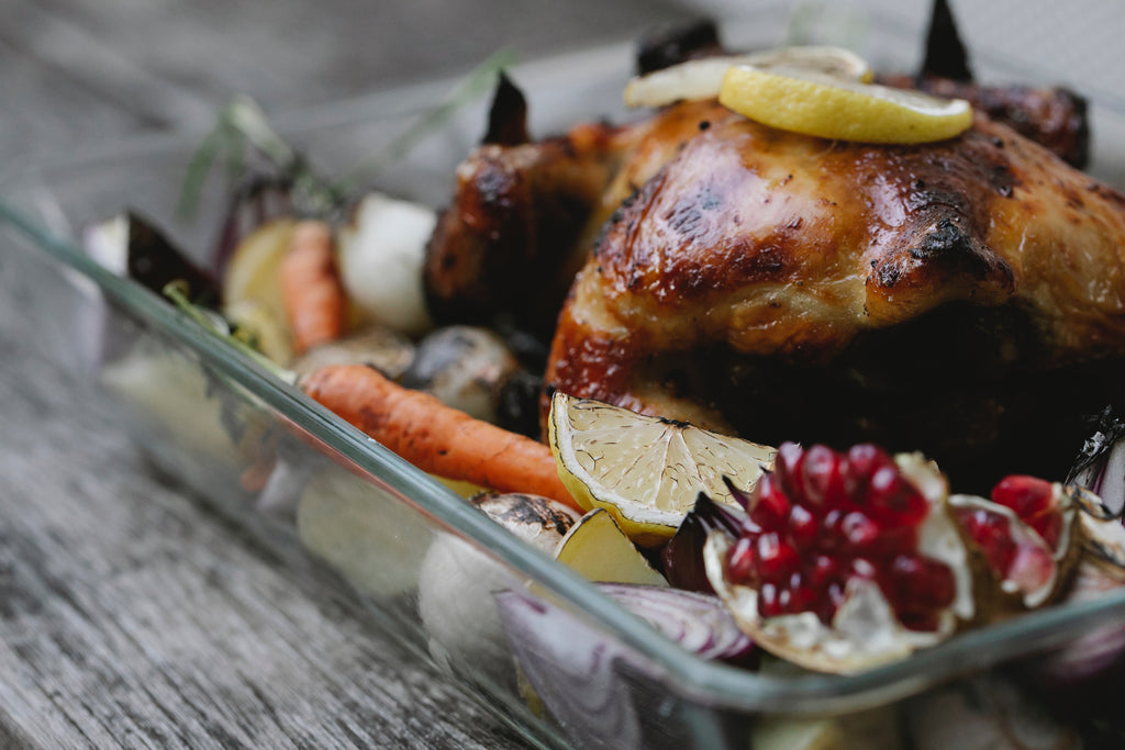 Roasted chicken with vegetables on the side on a roasting pan