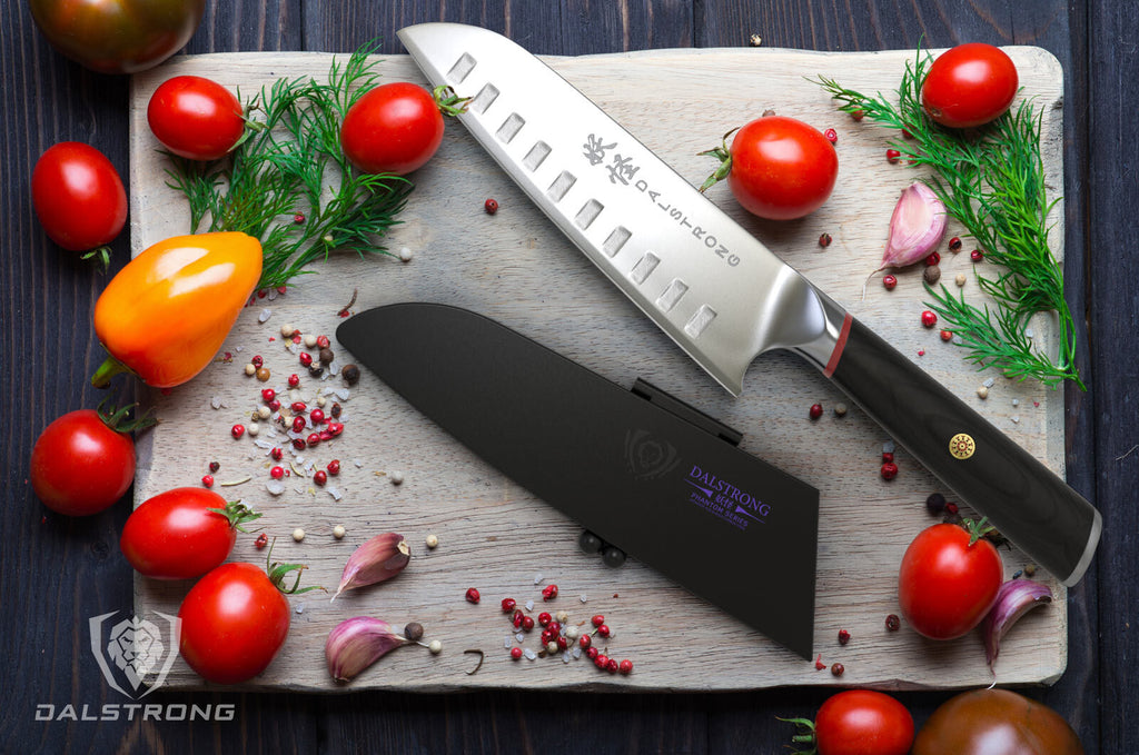 Japanese Style Santoku Knife on a cutting board next to cherry tomatoes garlic and other garnish