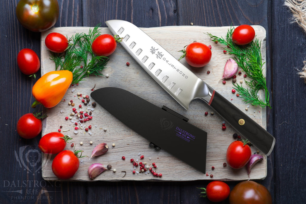 Japanese Style Santoku Knife on a cutting board next to cherry tomatoes garlic and other garnish