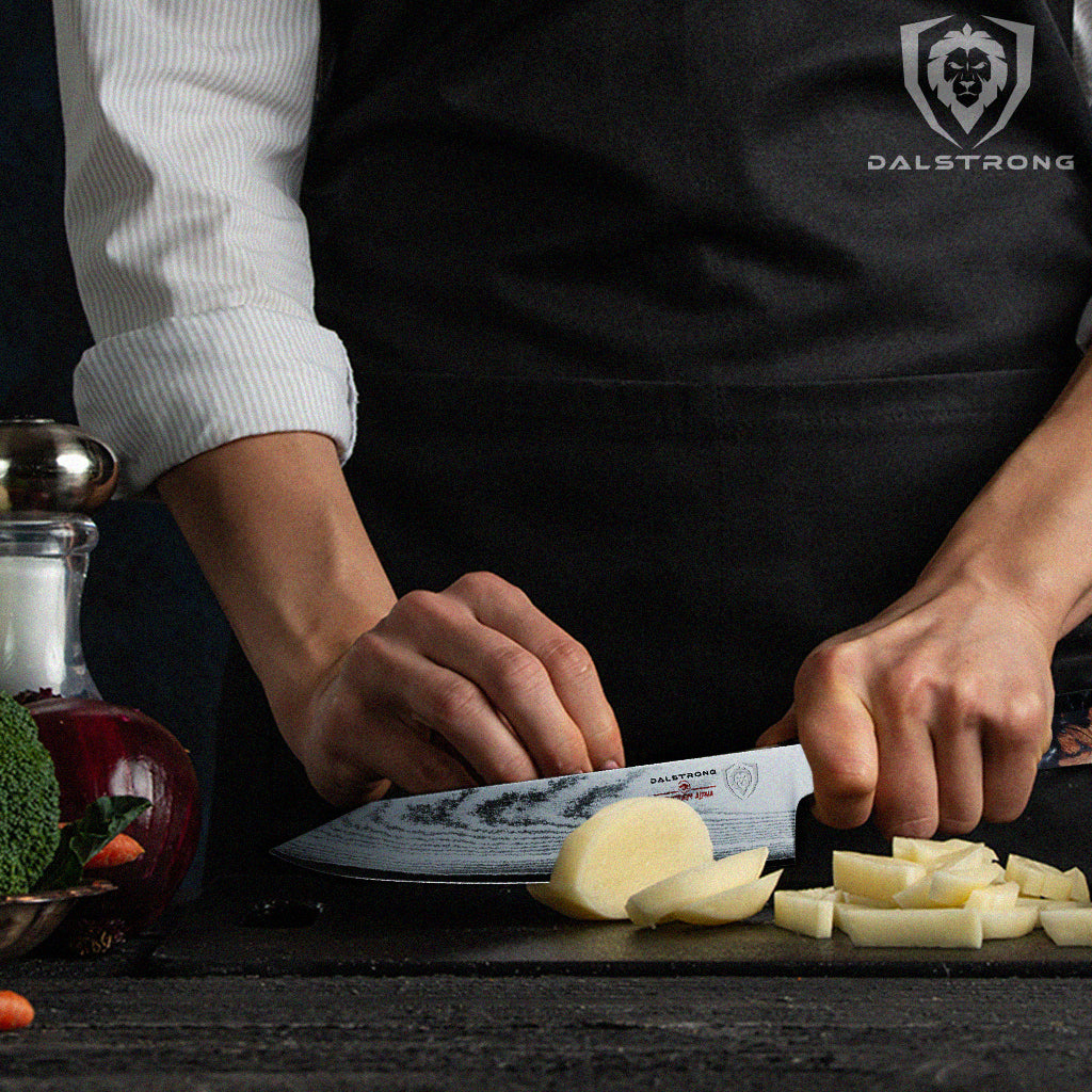 Close-up shot of a cook wearing a black apron dicing a raw potato using a Dalstrong Firestorm Alpha 8" Chef's Knife.