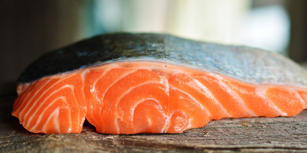 A well-lit photo of a fresh sliced salmon on a wooden table.