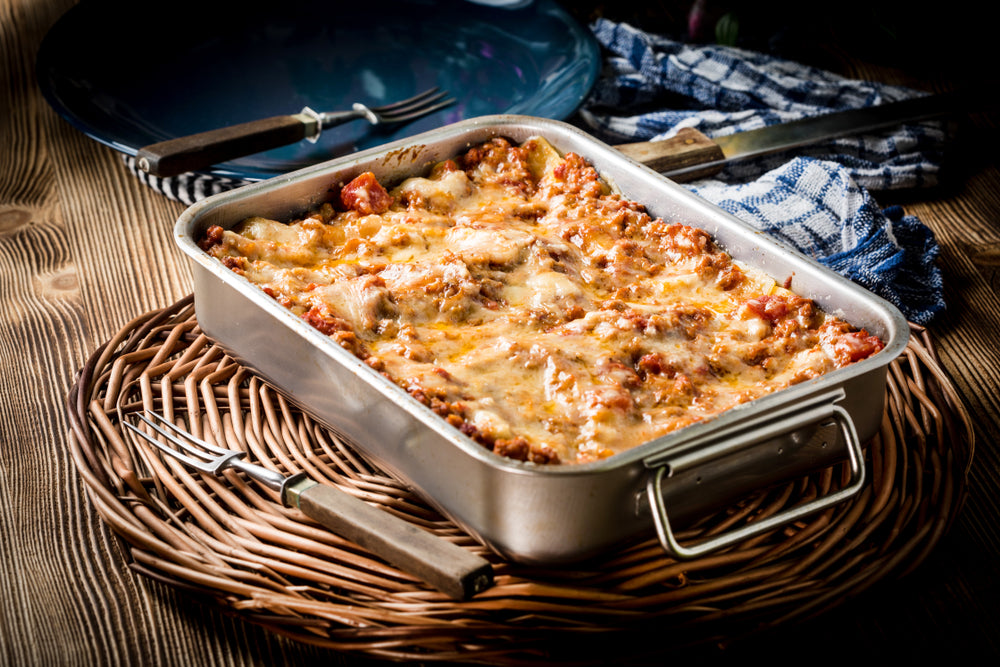 Baking tray filled with cooked lasagne on a brown table