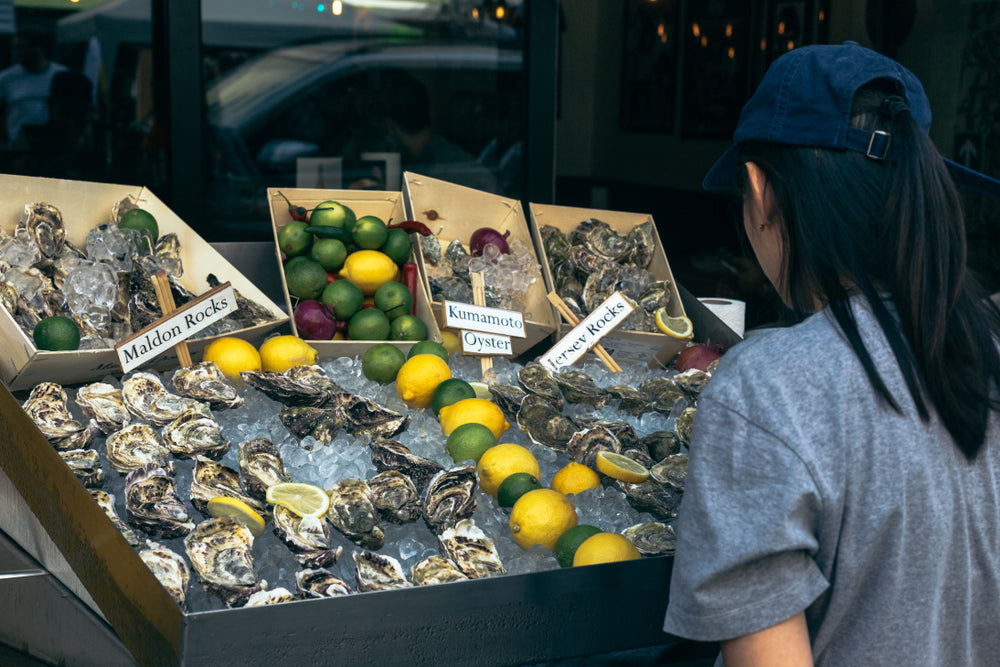 Woman in a hat choosing oysters at an outdoor market