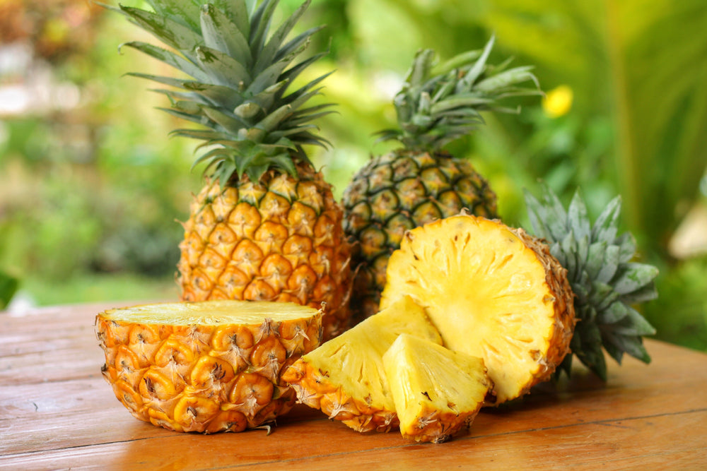 Sliced and half of Pineapple on wooden table with blurred garden background.