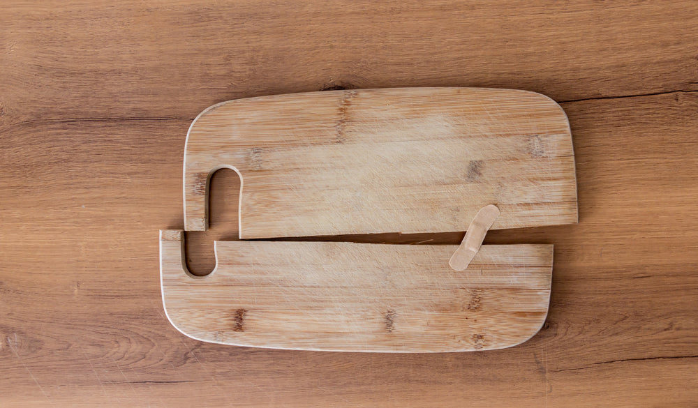 Old cutting board cracked in half and being held together with a plaster band aid