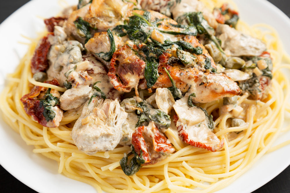 creamy tuscan chicken over spaghetti noodles