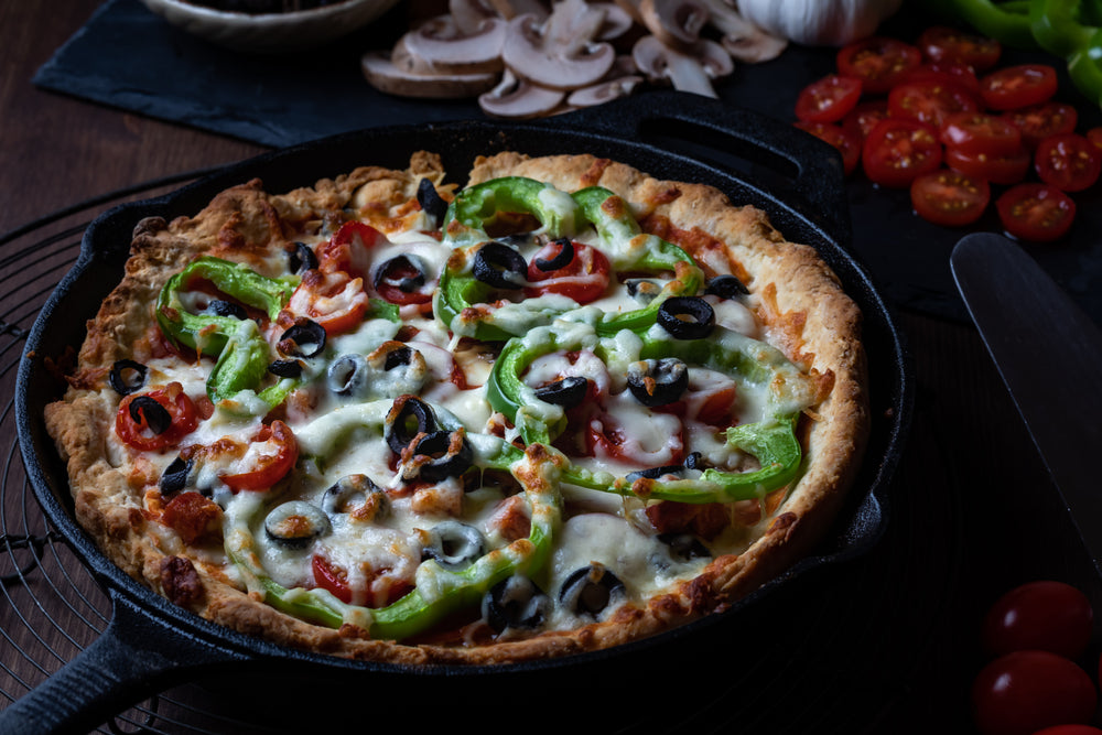 Deluxe Deep Dish Pizza in a black cast iron skillet on a black background