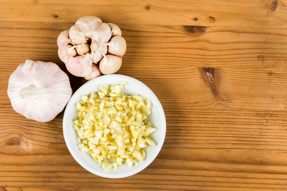 A bowl of finely minced garlic on a kitchen table