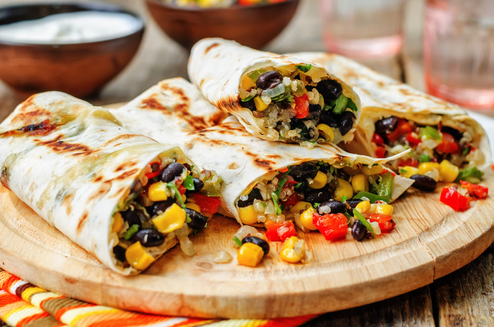 pepper corn black bean quinoa burritos on a dark wood background