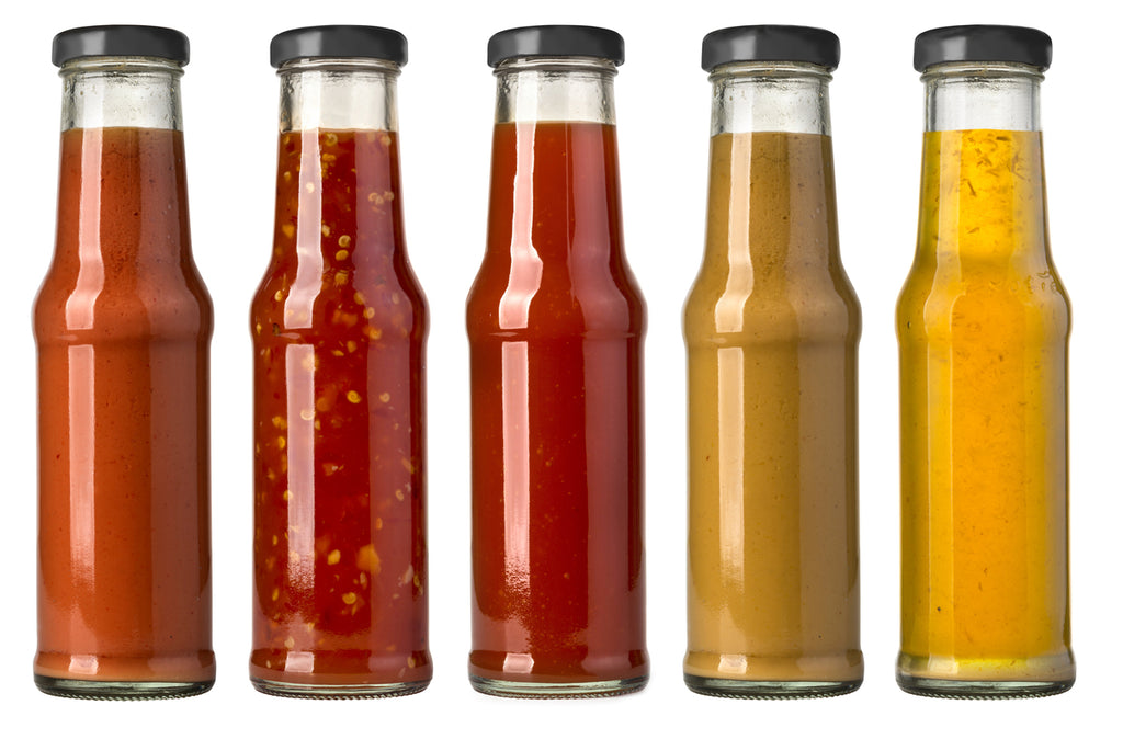 Five Capped Glass Bottles With Varying Colours from Orange to Red To Yellow. 