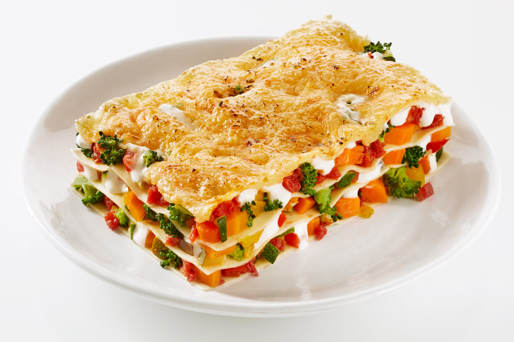 Healthy portion of fresh vegetable lasagne made with a mix of colorful fresh veggies served on a plate over a white background