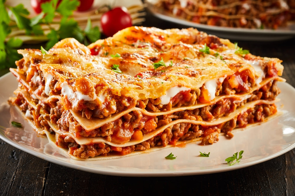 Portion of succulent ground beef lasagne topped with melted cheese and garnished with fresh parsley served on a plate in a close up view