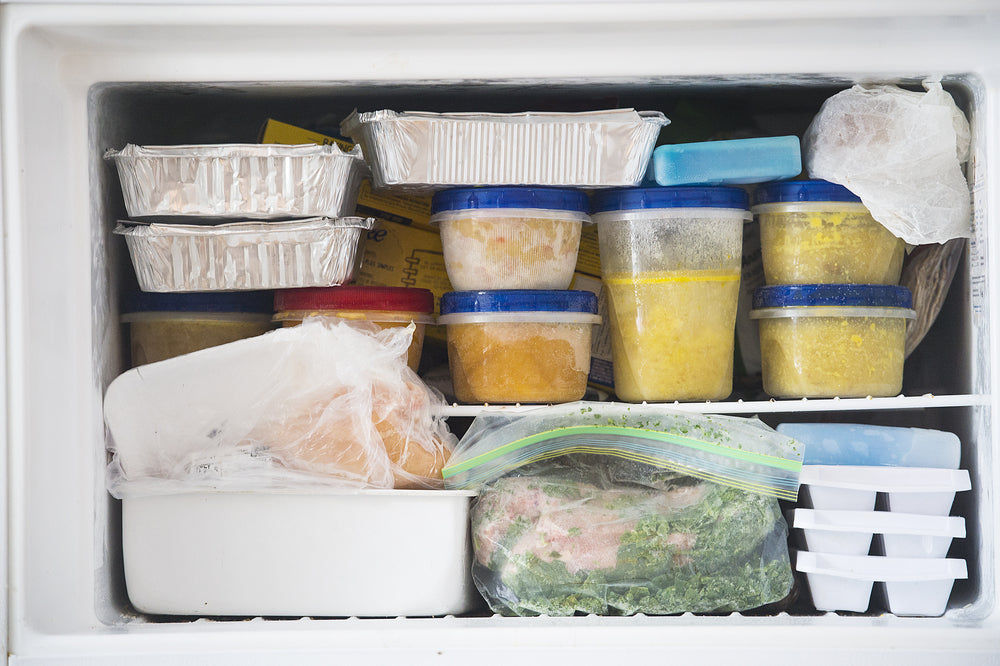 A freezer packed with various types of frozen food such as soups and vegetables