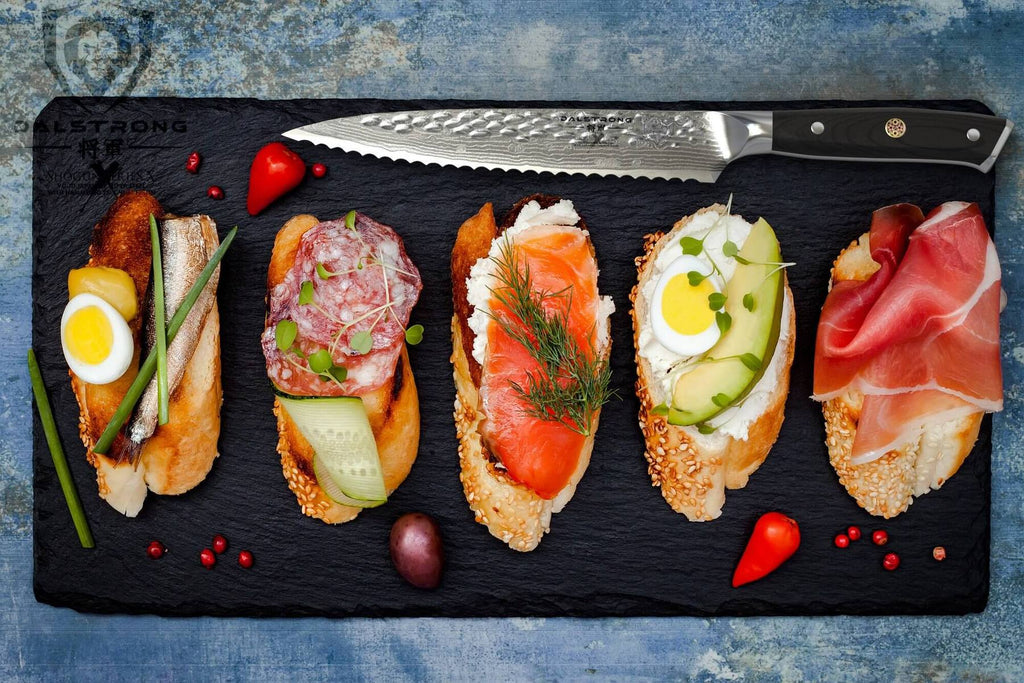 4 sandwiches on a black cutting board next to a serrated utility knife