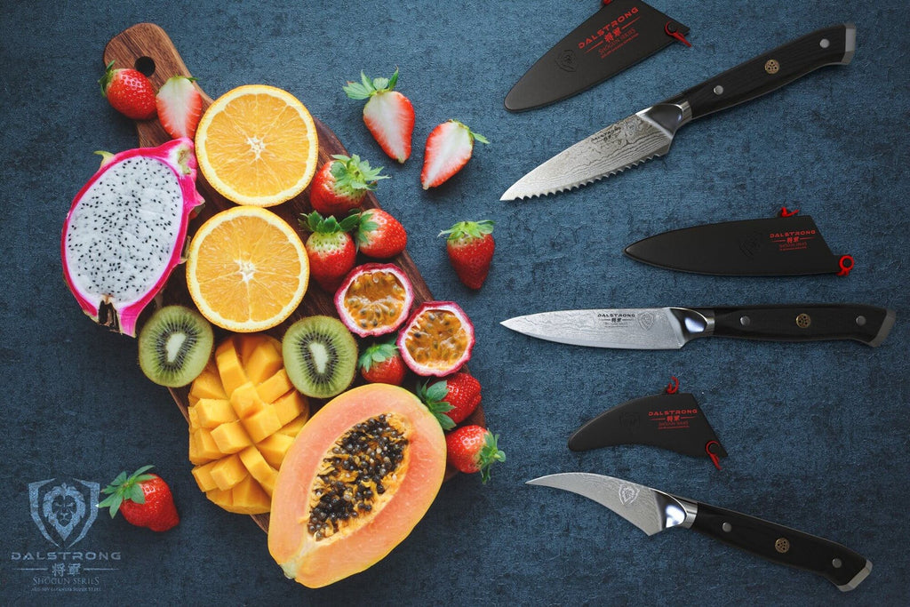A pile of sliced and chopped fruit next to three sharp paring knives