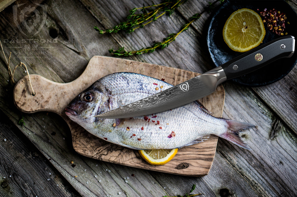 Small fillet knife resting on an uncooked fish that is laying on a small wooden cutting board