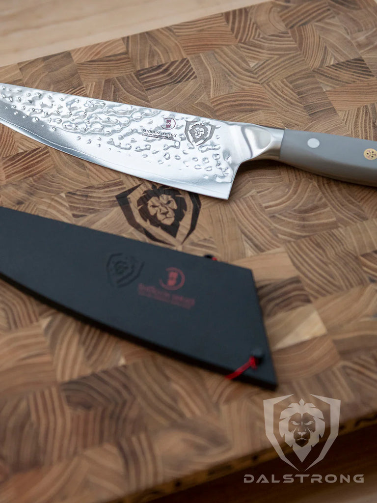 Shogun Series ELITE Chef's Knife 8" beside it's sheath on a dalstrong cutting board.