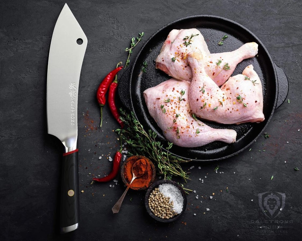 Dalstrong Phantom Series Crixus knife beside a plate full of raw cuts of chicken with herbs, chili, and seasonings on the side.