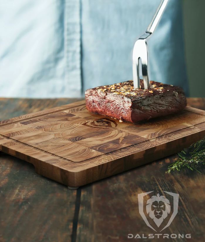Dalstrong Teak Cutting board with a steak on top
