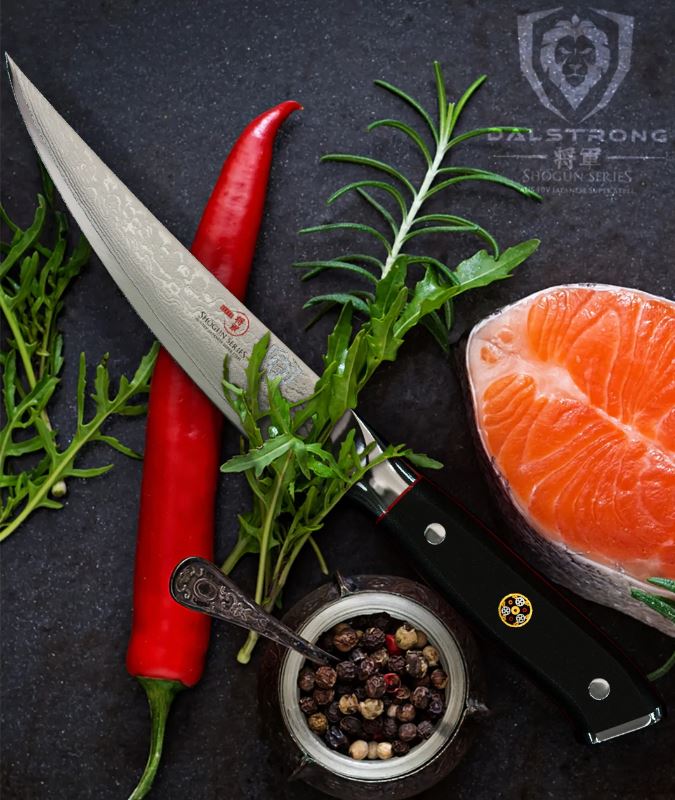 Dalstrong Shogun Series Fish Fillet beside a slice of fish, red chilli, bowl of peppercorns, and herbs on top.