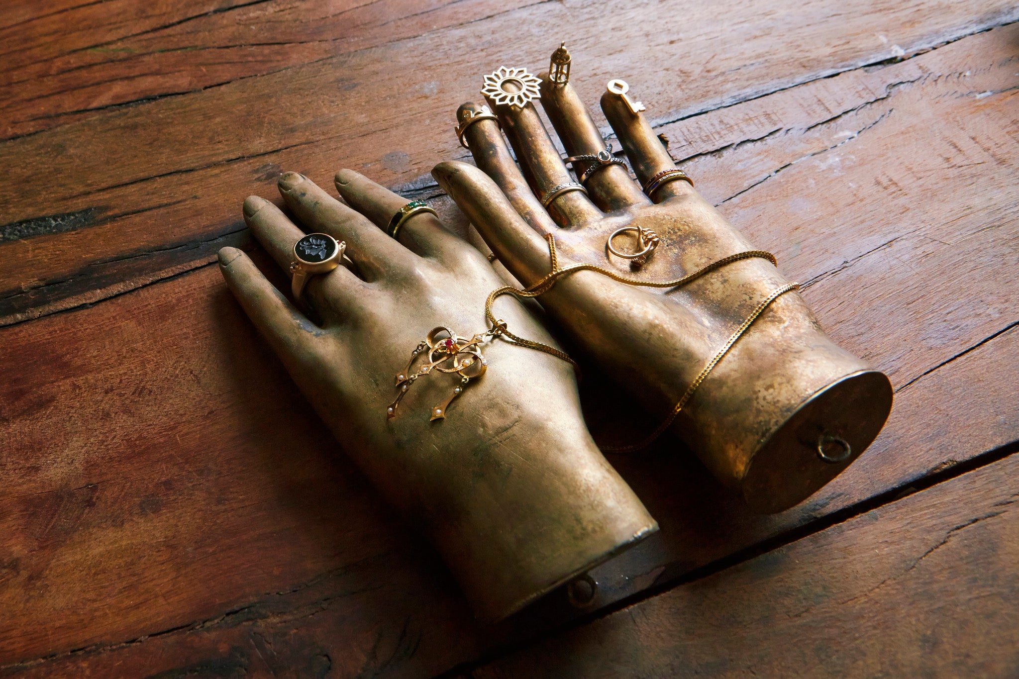 gillian steinhardt jewelry draped over model hands on a wood background