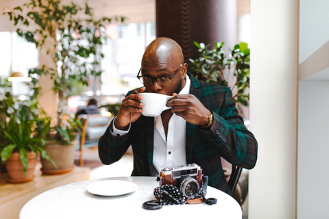 A man sips coffee out of a large mug while looking happy.