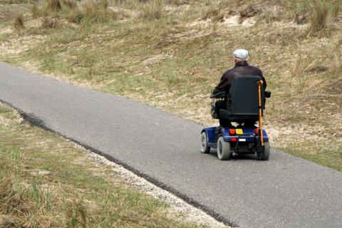 Senior man riding mobility scooter outdoors