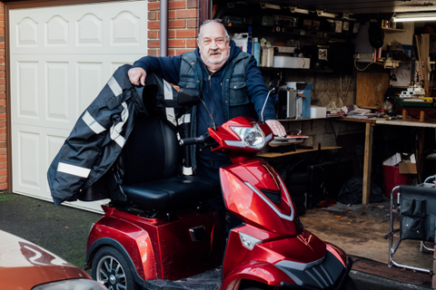 Man standing next to his red scooter