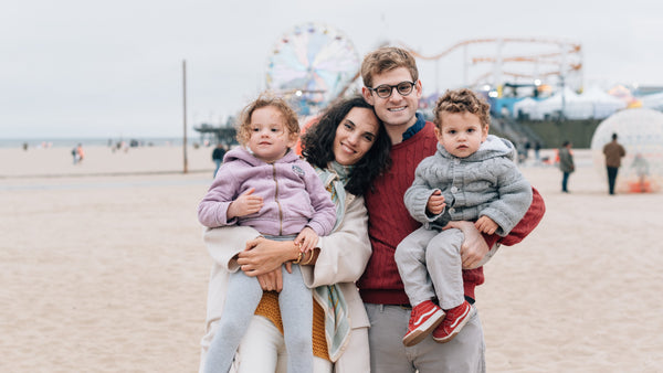 A family poses in front of a theme park at the beach. Family, travel tips.