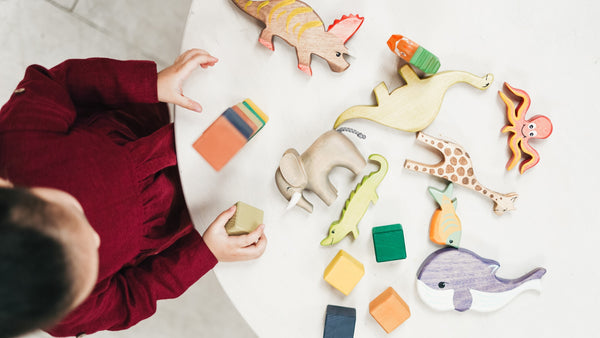 Top view of a girl playing with animal toys. Dinosaurs, fun activities, education, children books.