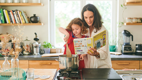 A Mom is reading and cooking with her young daughter. Children books, fun activities, educational.