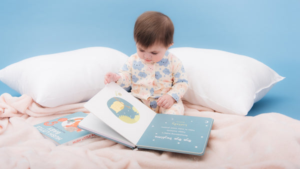 A baby is looking at a picture book. Bedtime stories, kids activities, educational.