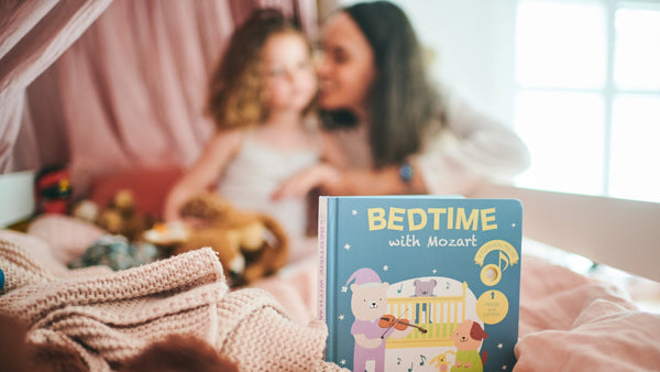 A bedtime book is in the front and a Mom and her daughter are in the background. Bedtime stories, kids activities, educational.