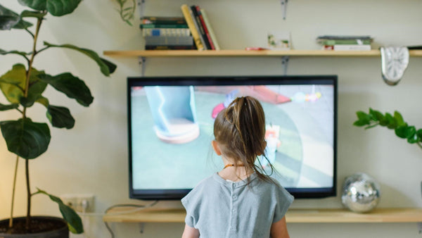 A girl is watching tv in her living room. Screentime, kids activities, fun, educational.
