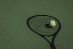 Tennis racquet shadow on grass with tennis ball