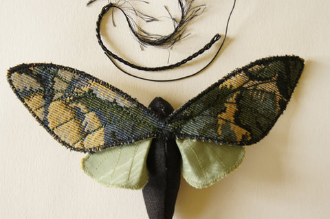 top view of moth with a piece each of cotton cord, braided cord and feather trim as choices for antennae