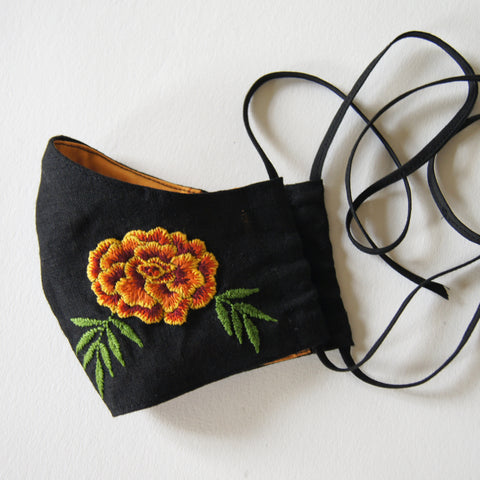 black linen mask with orange lining and marigold embroidery on the left side