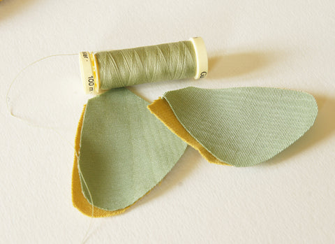 two cut pieces underwings in green satin, placed on two yellow cotton backing pieces