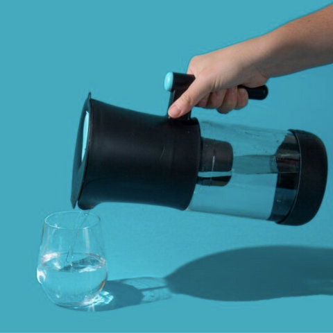 Hand pouring water from phox V2 water filter jug into glass