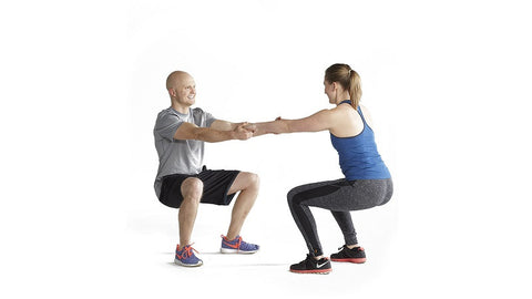 couple does a squat facing each other holding hands