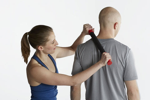 woman uses tiger tail massager on mans upper shoulder