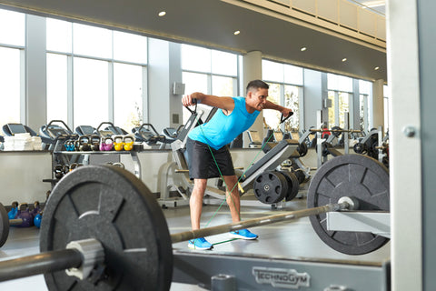 man does lateral raises in gym with Xertube