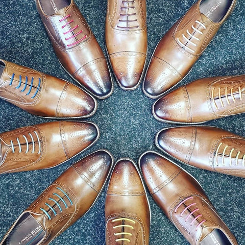 A birds eye view of ten Arthur Oxford Shoes in Chestnut from London brogue placed in a circle with the toes facing inwards, each with a different coloured lace