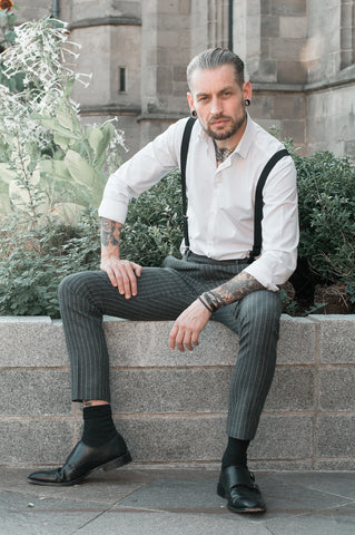 A man sat on a wall wearing Leonard monk shoes in black leather