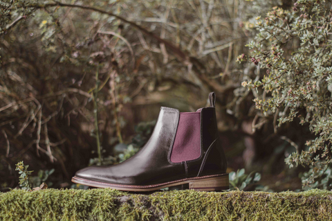 London Brogues hamilton chelsea boot in black leather with bordo elastic side panel on top of a hedge.