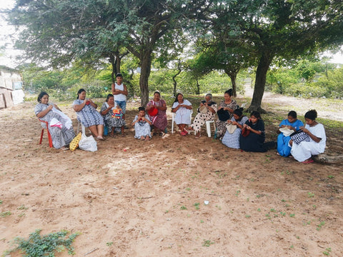 wayuu artisans from colombia making bags under a big tree