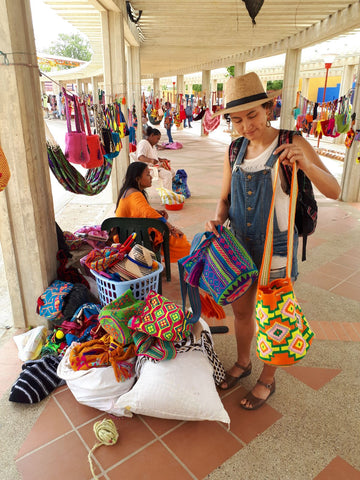 valentina pinzon, the owner of indiarts, holding wayuu bags in front of a vendor. buying directly from the artisans
