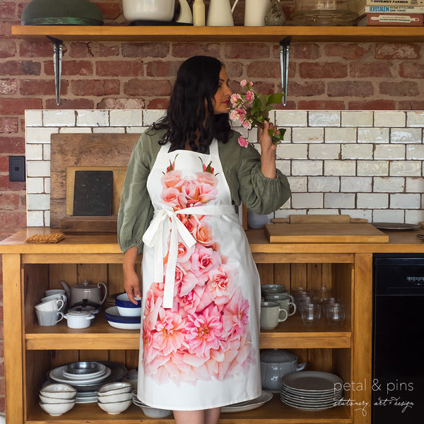 petal & pins floral apron featuring a design of Cecile Brunner roses modelled in the kitchen at The Woolrooms in Tasmania against a wooden bench