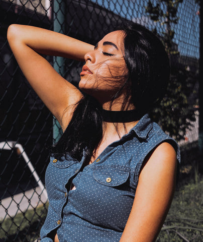 Woman-wearing-a-denim-shirt-lifting-her-arm-wearing-a-black-velvet-choker