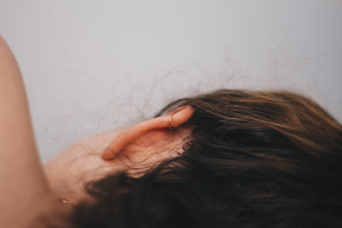 Girl-lying-on-her-side-with-a-helix-peircing-after-using-piercing-bump-treatment-oil